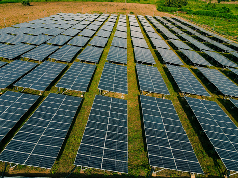 Aerial view of a large solar farm with rows of photovoltaic panels installed on a grassy field in Ogun State Nigeria.