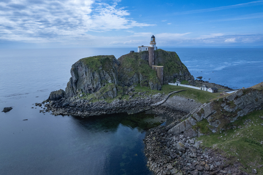 Aerial view of Sanda Island lighthouse perched on a rocky cliff surrounded by the sea near the Mull of Kintyre Argyll and Bute Council Scotland United Kingdom.