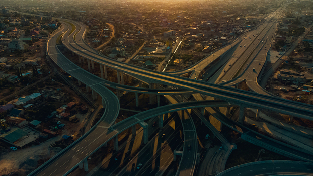 Aerial view of the multi level Pokuase Interchange featuring sweeping concrete ramps and highway lanes under warm golden hour light Ga North Municipal Greater Accra Region Ghana. Aerial view of the multi level Pokuase Interchange featuring sweeping concrete ramps and highway lanes under warm golden hour light Ga North Municipal Greater Accra Region Ghana.