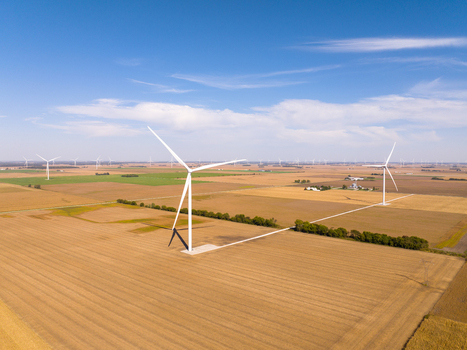 Aerial view of wind turbines in a vast agricultural field under a clear blue sky in Wolcott Indiana United States.