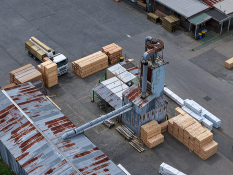 Melbourne Australia 25 September 2026 Aerial view of a lumber yard with stacks of timber a truck being loaded and industrial machinery with rusted metal roofs.