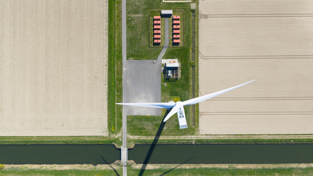 Drone view of wind turbines and a battery storage facility distributing renewable energy supporting grid balance clean power infrastructure and sustainable electricity supply.
