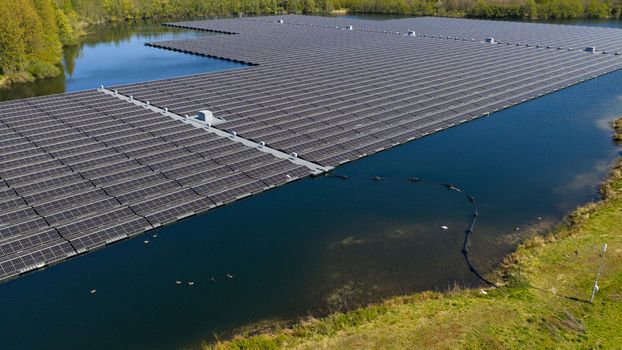 Aerial view of a massive floating solar farm on a calm lake surrounded by lush green trees and grassy banks in Zwolle Overijssel Netherlands. Aerial view of a massive floating solar farm on a calm lake surrounded by lush green trees and grassy banks in Zwolle Overijssel Netherlands.