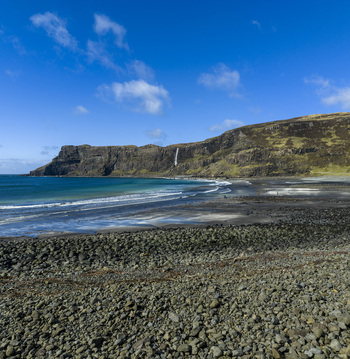 Aerial view of Talisker Bay Beach with dark sand and a waterfall cascading down the cliffs in Isle of Skye Scotland United Kingdom. Aerial view of Talisker Bay Beach with dark sand and a waterfall cascading down the cliffs in Isle of Skye Scotland United Kingdom.