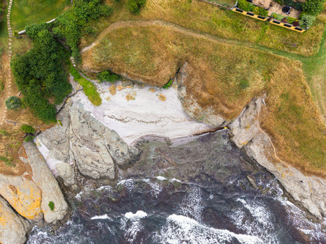 Aerial view of a small sandy beach nestled between rocky cliffs and grassy terrain along the Black Sea coast in Lozenets Burgas Bulgaria.
