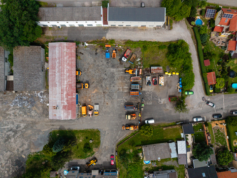 Aerial view of a construction yard featuring heavy machinery trucks and industrial equipment parked on a gravel lot in Zebrak Central Bohemian Region Czechia. Aerial view of a construction yard featuring heavy machinery trucks and industrial equipment parked on a gravel lot in Zebrak Central Bohemian Region Czechia.