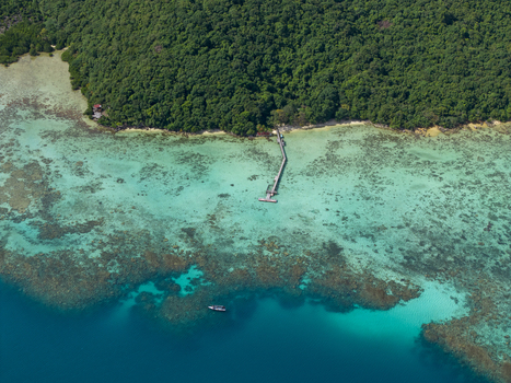 Aerial view of a pier stretching into the turquoise sea from a lush green island at Turtle Conservation Karimunjawa Central Java Indonesia.