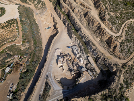 Aerial view of an industrial stone quarry with processing machinery dirt access roads and excavated rock faces in Teulada Valencian Community Spain.