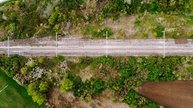 Aerial view of the railway tracks cutting through vibrant green foliage and cultivated fields creating a stark contrast of natural and man made elements Sremska Mitrovica Vojvodina Serbia. Aerial view of the railway tracks cutting through vibrant green foliage and cultivated fields creating a stark contrast of natural and man made elements Sremska Mitrovica Vojvodina Serbia.