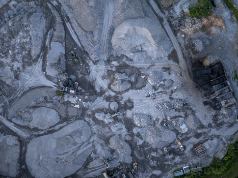 Aerial view of an industrial quarry site featuring piles of gravel sand and heavy machinery operating within the extraction area in Charleroi Wallonia Belgium.