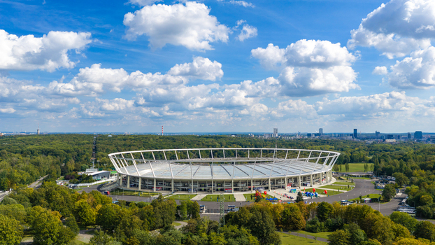 Chorzow Silesian Voivodeship Poland 17 September 2026 Aerial view of Silesian Stadium surrounded by lush green parkland and trees under a bright blue sky with scattered white clouds.