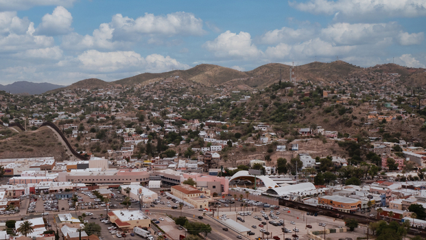 Aerial view of the U.S. Mexico border wall dividing Nogales Arizona United States and Nogales Sonora Mexico across an urban desert landscape and hilly terrain.