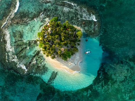 Aerial view of Guyam Island with lush palm trees white sand beach and turquoise waters surrounded by coral reefs in General Luna Caraga Philippines. Aerial view of Guyam Island with lush palm trees white sand beach and turquoise waters surrounded by coral reefs in General Luna Caraga Philippines.