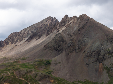 Aerial view of Mount Sneffels in the San Juan Mountain Range with rugged rocky slopes alpine terrain and the winding Yankee Boy Basin trail in Ouray Colorado United States. Aerial view of Mount Sneffels in the San Juan Mountain Range with rugged rocky slopes alpine terrain and the winding Yankee Boy Basin trail in Ouray Colorado United States.
