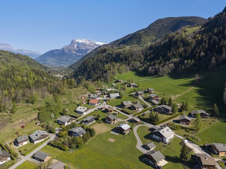 Saint Gervais les Bains France 30 April 2026 Aerial view of Saint Gervais les Bains village with traditional chalets lush green meadows and snow capped Alpine peaks under a clear blue sky.