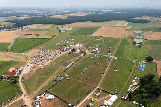 Aerial view of the Open Beatz Festival grounds featuring stages tents and parking areas surrounded by green fields and forests in Herzogenaurach Bayern Germany. Aerial view of the Open Beatz Festival grounds featuring stages tents and parking areas surrounded by green fields and forests in Herzogenaurach Bayern Germany.