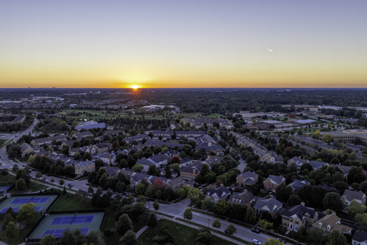 Aerial view of a residential neighborhood in Glenview featuring tennis courts in the foreground during a vibrant sunset in Glenview Illinois United States. Aerial view of a residential neighborhood in Glenview featuring tennis courts in the foreground during a vibrant sunset in Glenview Illinois United States.