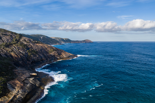 Aerial view of the rugged coastline at Salmon Holes featuring dramatic granite cliffs deep blue ocean waters and crashing waves in Torndirrup Western Australia Australia.