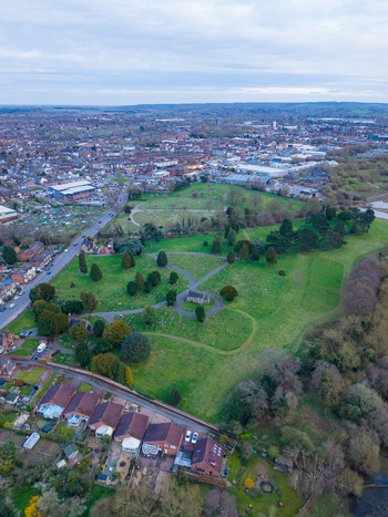 Aerial view of Doxey Marshes featuring green fields scattered trees a small historic cemetery and surrounding residential streets in Stafford England United Kingdom. Aerial view of Doxey Marshes featuring green fields scattered trees a small historic cemetery and surrounding residential streets in Stafford England United Kingdom.