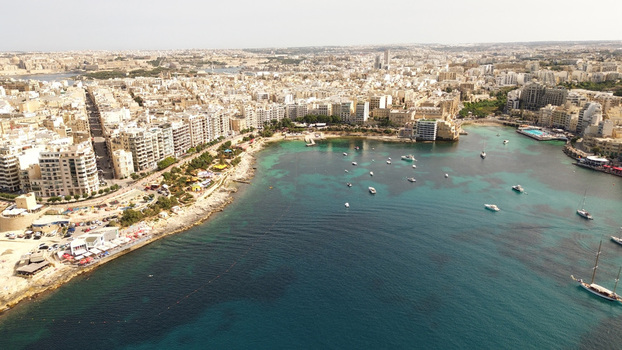 Aerial view of the coastal urban landscape of Sliema with dense residential buildings a vibrant bay filled with boats and turquoise Mediterranean waters in Malta. Aerial view of the coastal urban landscape of Sliema with dense residential buildings a vibrant bay filled with boats and turquoise Mediterranean waters in Malta.