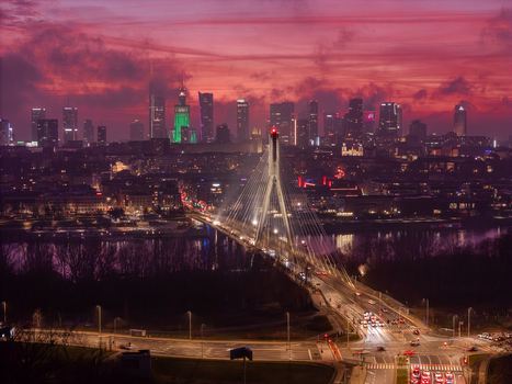 Aerial view of the Swietokrzyski Bridge with evening traffic and the illuminated city skyline under a dramatic pink sunset sky in Warsaw Poland. Aerial view of the Swietokrzyski Bridge with evening traffic and the illuminated city skyline under a dramatic pink sunset sky in Warsaw Poland.