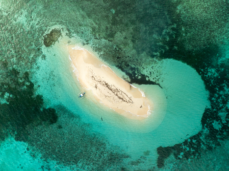 Aerial view of Naked Island surrounded by turquoise water and coral reefs with a small boat in Siargao Philippines. Aerial view of Naked Island surrounded by turquoise water and coral reefs with a small boat in Siargao Philippines.