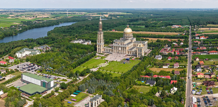 Aerial view of Basilica of Our Lady of Lichen surrounded by lush greenery a large plaza and nearby buildings in Lichen Stary Wielkopolskie Poland. Aerial view of Basilica of Our Lady of Lichen surrounded by lush greenery a large plaza and nearby buildings in Lichen Stary Wielkopolskie Poland.