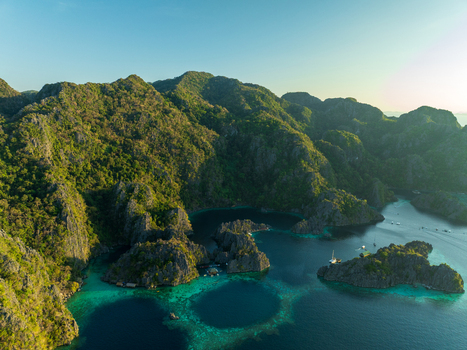 Aerial view of Twin Lagoon featuring dramatic limestone cliffs turquoise waters and lush vegetation in Coron Mimaropa Philippines. Aerial view of Twin Lagoon featuring dramatic limestone cliffs turquoise waters and lush vegetation in Coron Mimaropa Philippines.