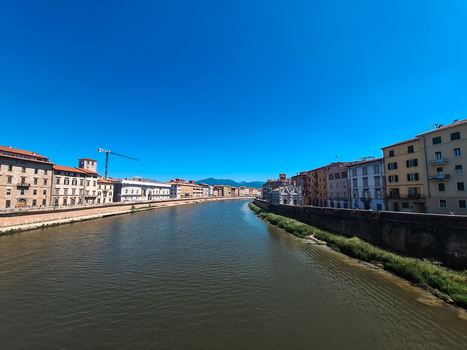 Pisa Italy 27 April 2026 View of the Arno River flowing through the historic city center of Pisa lined with traditional buildings stone embankments and a clear blue sky. Pisa Italy 27 April 2026 View of the Arno River flowing through the historic city center of Pisa lined with traditional buildings stone embankments and a clear blue sky.