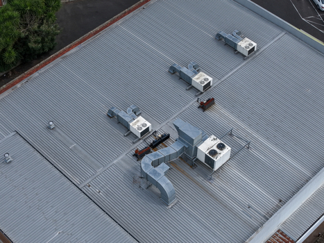 Aerial view of industrial metal roof with HVAC units and ventilation ductwork in Melbourne VIC Australia.