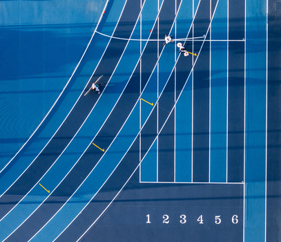 Aerial view of a blue running track with athletes training on the lanes marked with white lines and numbers in Santo Domingo Distrito Nacional Dominican Republic.