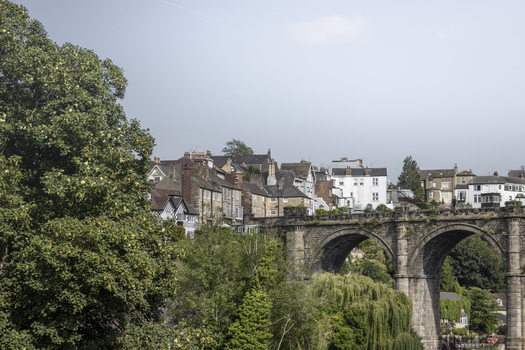 View of the historic Knaresborough Viaduct with traditional stone houses and lush green trees in Knaresborough England United Kingdom.