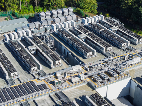 Aerial view of a data center rooftop featuring rows of industrial HVAC cooling units solar panel arrays and technical infrastructure in the United Kingdom.