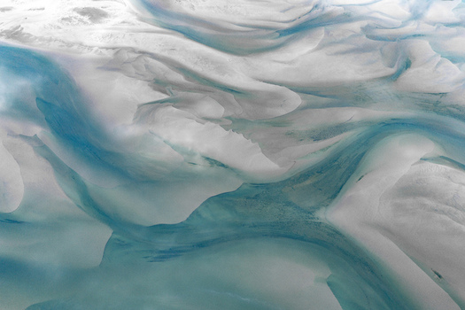 Aerial view of the snow covered landscape of Senja featuring intricate patterns of frozen water and glacial textures in shades of white and blue in Senja Troms Norway.