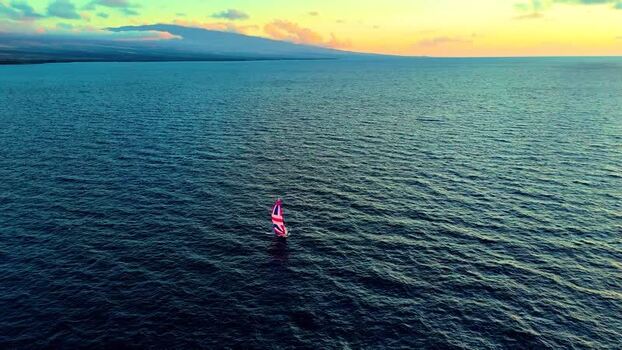 Aerial view of a sailboat on the blue ocean at sunset United States. Aerial view of a sailboat on the blue ocean at sunset United States.
