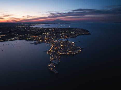 Aerial view of the Island of Ortigia with city lights at dusk and Mount Etna in the distance Syracuse Sicily Italy. Aerial view of the Island of Ortigia with city lights at dusk and Mount Etna in the distance Syracuse Sicily Italy.