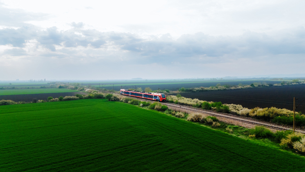 Aerial view of a train cutting through a vibrant green and dark brown landscape under a soft overcast sky Sremska Mitrovica Vojvodina Serbia. Aerial view of a train cutting through a vibrant green and dark brown landscape under a soft overcast sky Sremska Mitrovica Vojvodina Serbia.