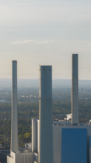 Aerial view of the Grosskraftwerk Mannheim power plant with its tall industrial chimneys and infrastructure surrounded by lush greenery in Mannheim Baden Wurttemberg Germany.