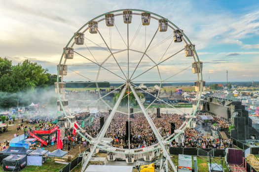 Herzogenaurach Germany 24 July 2025 Aerial view of Open Beatz Festival featuring a large ferris wheel overlooking a massive crowd stages and festival grounds under a bright sky.