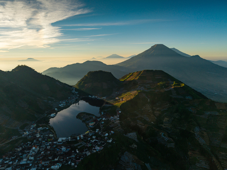 Aerial view of Telaga Cebong lake nestled among volcanic mountains and terraced agricultural fields near the village of Sikunang in Kecamatan Kejajar Jawa Tengah Indonesia.