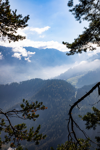 Aerial view of the Swiss Alps near Airolo featuring lush pine forests misty valleys and rugged mountain peaks under a bright blue sky in Airolo Ticino Switzerland. Aerial view of the Swiss Alps near Airolo featuring lush pine forests misty valleys and rugged mountain peaks under a bright blue sky in Airolo Ticino Switzerland.