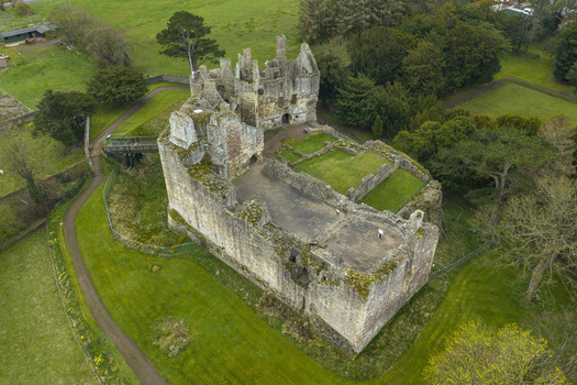 Aerial view of the historic Dirleton Castle and Gardens featuring ruined stone walls and lush green lawns in Dirleton Scotland United Kingdom. Aerial view of the historic Dirleton Castle and Gardens featuring ruined stone walls and lush green lawns in Dirleton Scotland United Kingdom.