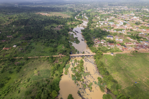 Aerial view of the muddy river cutting through verdant forests and the town with a bridge standing firm Asejire Oyo Nigeria. Aerial view of the muddy river cutting through verdant forests and the town with a bridge standing firm Asejire Oyo Nigeria.