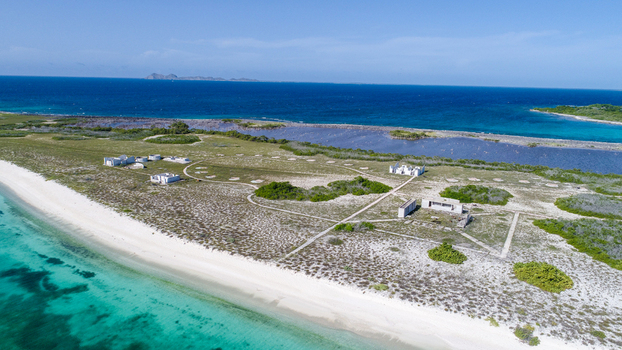 Aerial view of Los Roques archipelago with white sandy beaches turquoise Caribbean waters and small coastal structures on a flat island Los Roques Dependencias Federale Venezuela. Aerial view of Los Roques archipelago with white sandy beaches turquoise Caribbean waters and small coastal structures on a flat island Los Roques Dependencias Federale Venezuela.