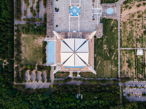 Aerial view of Faisal Masjid with its iconic white triangular roof and four minarets surrounded by green landscapes and parking lots in Islamabad Islamabad Capital Ter Pakistan. Aerial view of Faisal Masjid with its iconic white triangular roof and four minarets surrounded by green landscapes and parking lots in Islamabad Islamabad Capital Ter Pakistan.