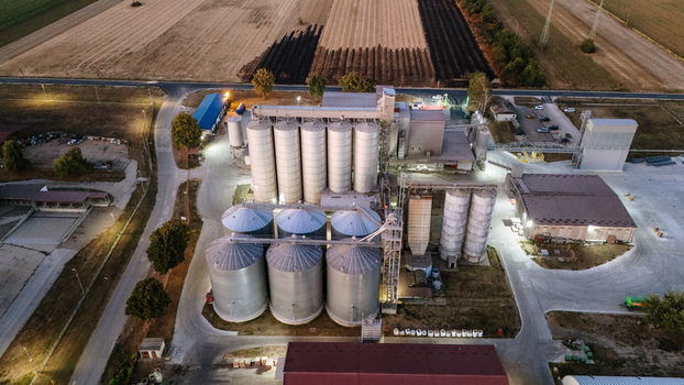 Aerial view of a large industrial grain silo facility illuminated at night surrounded by agricultural fields and roads in Sremska Mitrovica Vojvodina Serbia. Aerial view of a large industrial grain silo facility illuminated at night surrounded by agricultural fields and roads in Sremska Mitrovica Vojvodina Serbia.