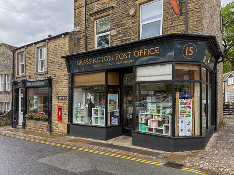 Hawes United Kingdom 06 July 2025 View of the Grassington Post Office and The Wine Shop in traditional stone buildings along a paved street. Hawes United Kingdom 06 July 2025 View of the Grassington Post Office and The Wine Shop in traditional stone buildings along a paved street.