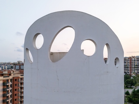 Alges Portugal 25 July 2026 Aerial view of the modern bell tower of the Santissima Trindade Church featuring circular openings with urban residential buildings in the background.