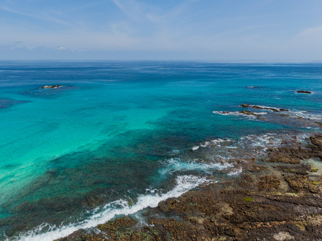 Aerial view of turquoise waters meet rugged rocky shores under the vast blue sky Erissel Socotra Yemen.