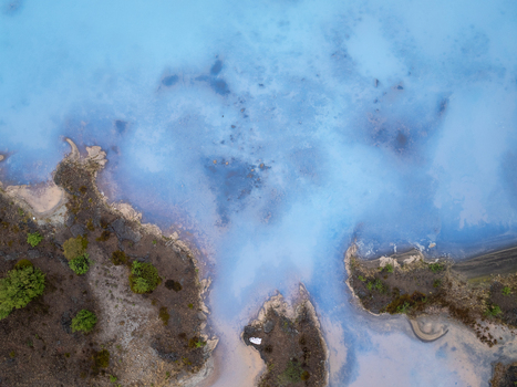 Aerial view of the geothermal landscape at Hverir with steaming blue mineral pools rugged volcanic terrain and sparse vegetation in Reykjahlid Thingeyjarsveit Iceland. Aerial view of the geothermal landscape at Hverir with steaming blue mineral pools rugged volcanic terrain and sparse vegetation in Reykjahlid Thingeyjarsveit Iceland.